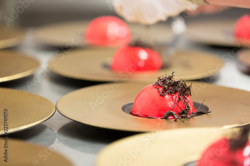 A red icecream desert topped with a decorative chocolate finish prepared by a gourmet chef. photo