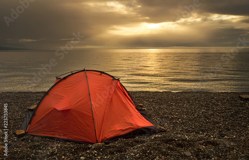 Tent near lake shore at the beautiful sunset
