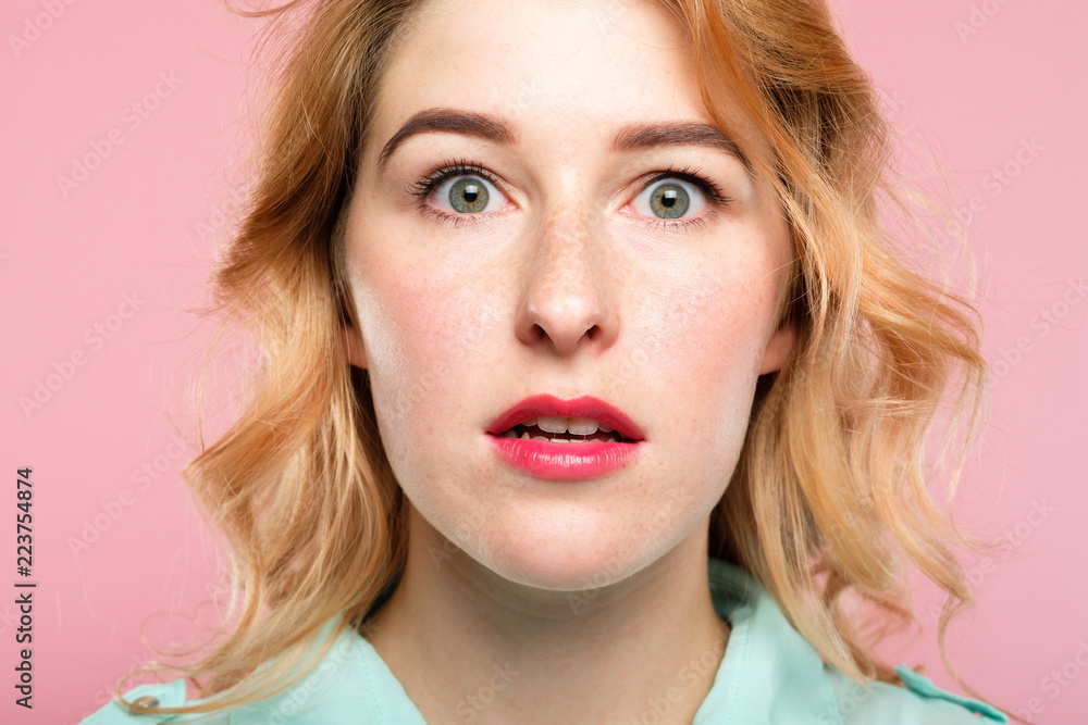 Naklejka premium surprised startled astonished amazed girl with open mouth. unbelievable news. young beautiful woman on pink background. emotional facial expression.