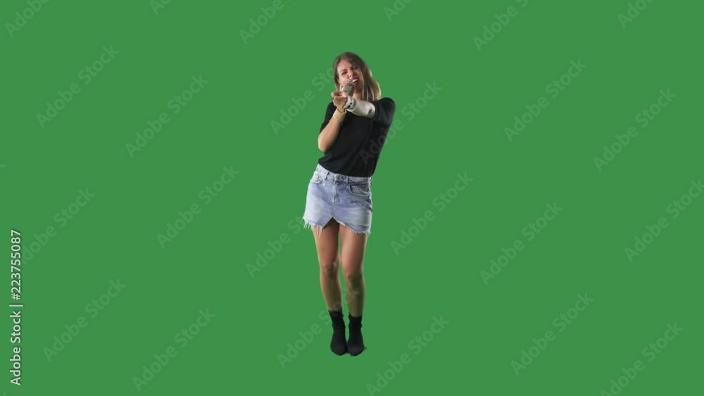 Young playful woman singing while holding cellphone as microphone. Full body isolated on green screen background. Young playful woman singing while holding cellphone as microphone. Full body isolated on green screen background.