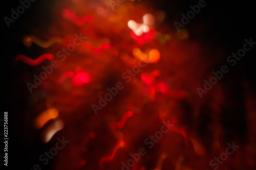 abstract lens flare on black background. red defocused bokeh lights. blurred christmas wallpaper decor. festive glowing christmas sparkler design.
