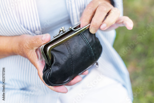hands of an elderly woman holding a purse with money, pension