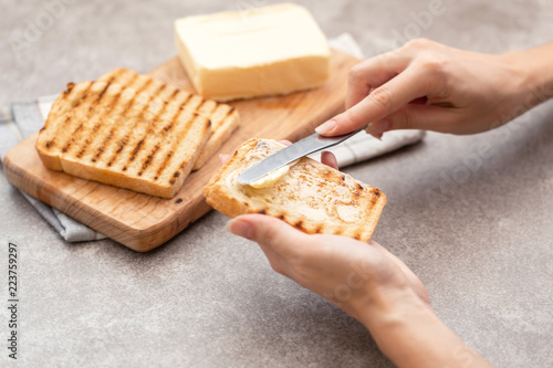 Female hand butters toasts for breakfast