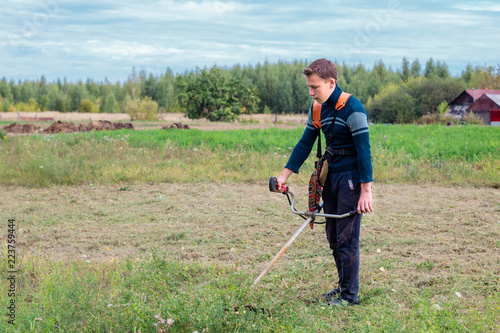 the young man mows the grass