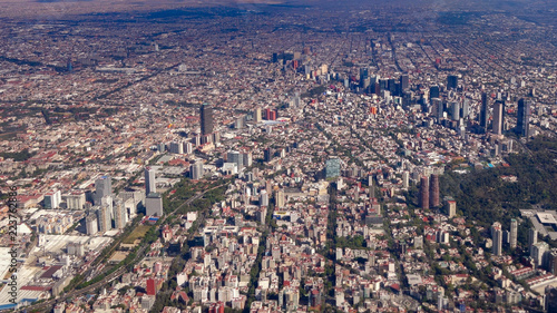 Mexico City, Mexico - Jan 2016: A Volaris passenger plane flies over the skyscrapers and parks of the central business district of Mexico City photo