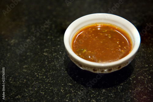 Fotografie Chinese sukiyaki sauce in little bowl on black floor