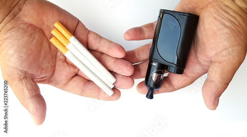 Vaping device and cigarettes in the man's hand, concept of choosing the type of cigarette photo