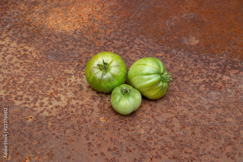 Green tomatoes not ideal from new harvest on rusty melallic surface background photo