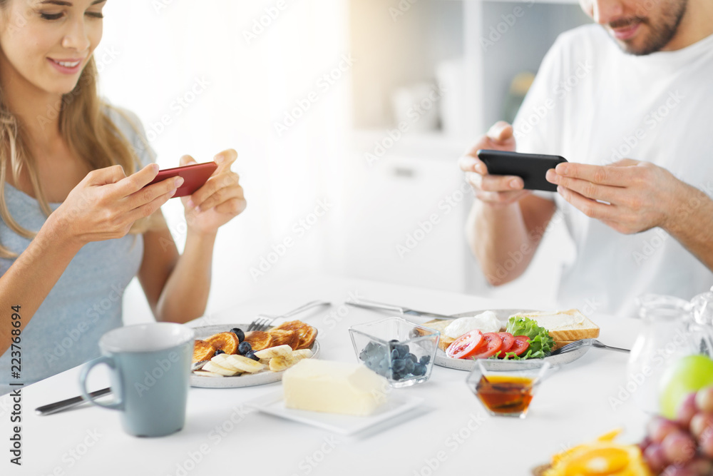 food and technology concept - close up of couple with smartphones having breakfast at home food and technology concept - close up of couple with smartphones having breakfast at home