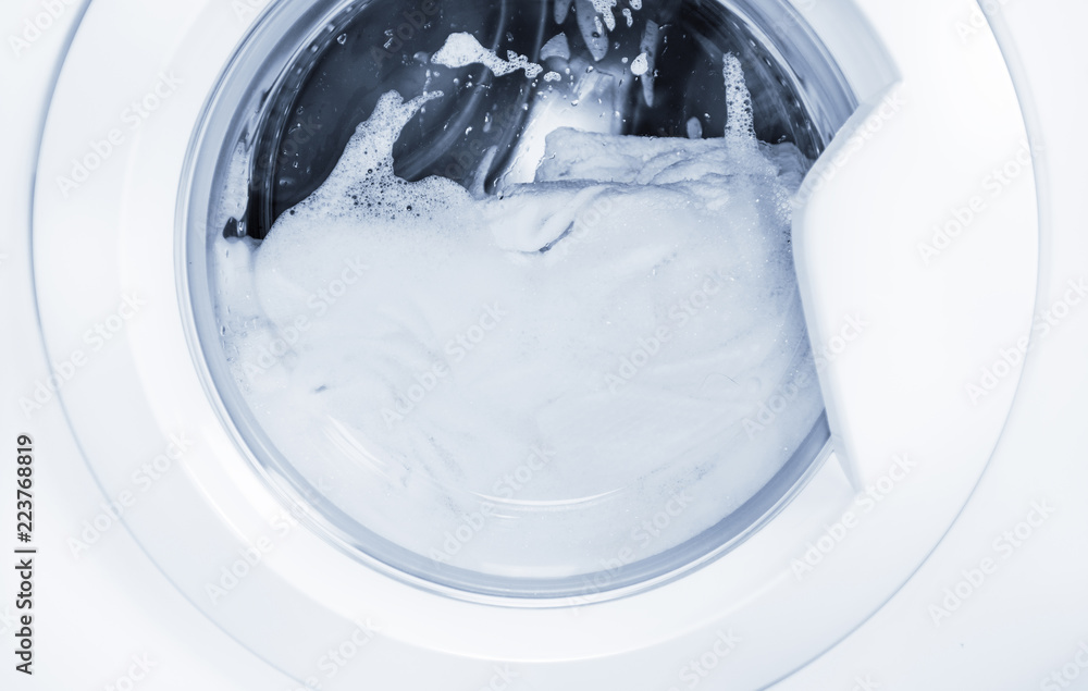 Process of cleaning white cloth in washing machine, stainless drum inside with wet towels,