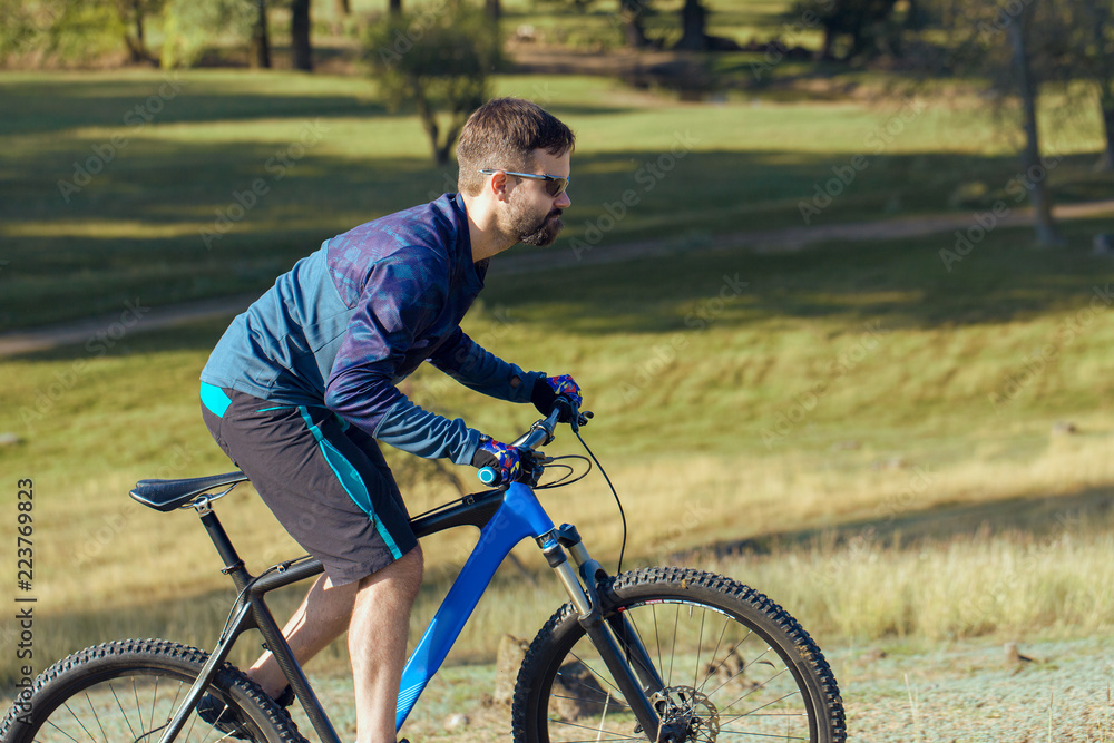 A cyclist rides the hills, Beautiful portrait of a guy on a blue bicycle A cyclist rides the hills, Beautiful portrait of a guy on a blue bicycle