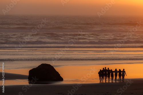 Sunset on Cannon Beach. Silhouettes of group of friends on the beach. Oregon  USA.