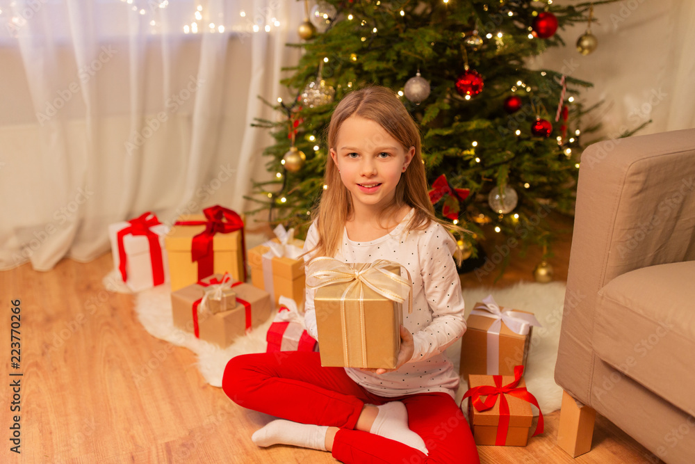 christmas, holidays and childhood concept - smiling girl with gift box at home christmas, holidays and childhood concept - smiling girl with gift box at home