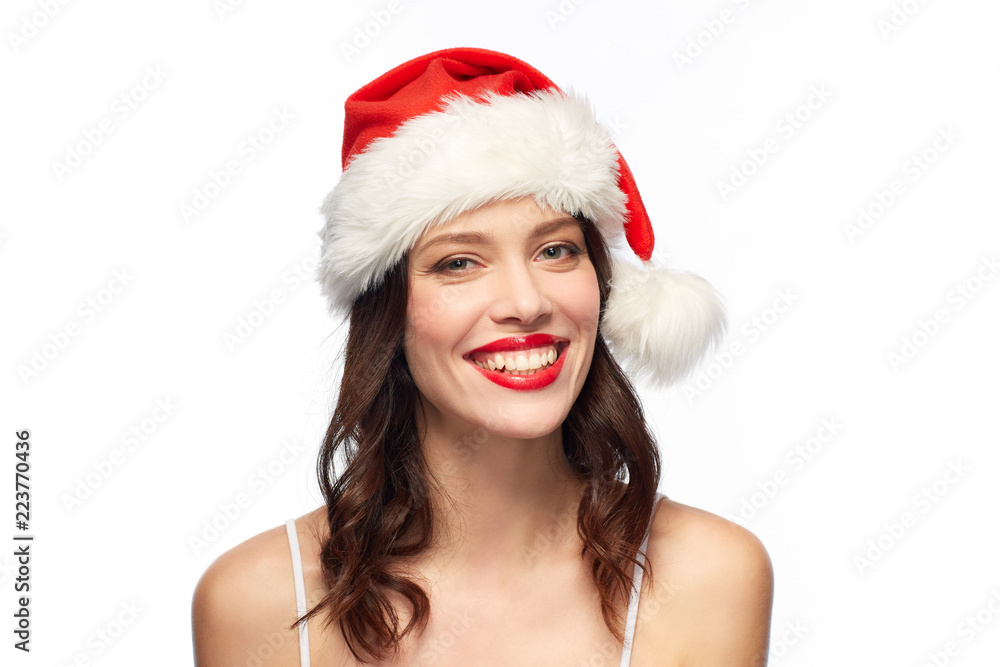 beauty, christmas and people concept - happy smiling young woman with red lipstick in santa hat over white background beauty, christmas and people concept - happy smiling young woman with red lipstick in santa hat over white background
