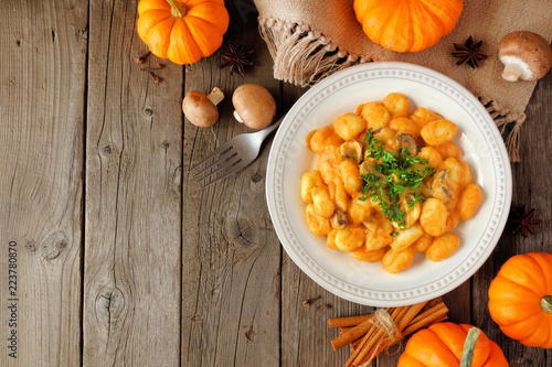 Gnocchi with a pumpkin, mushroom cream sauce. Autumn meal. Top view table scene on a rustic wood background with copy space. photo