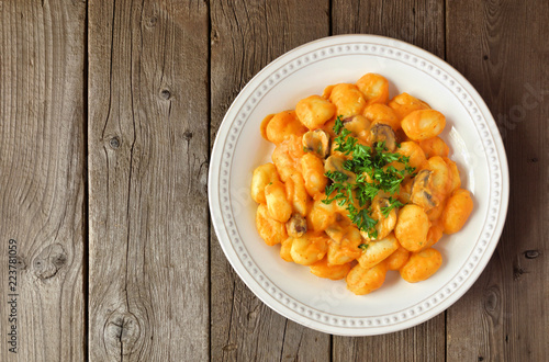 Gnocchi with a pumpkin, mushroom cream sauce. Autumn meal. Above view on a rustic wood background.