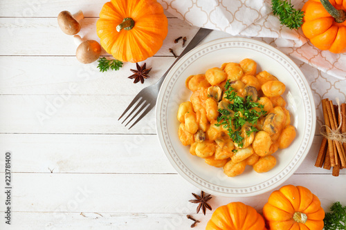 Gnocchi with a pumpkin, mushroom cream sauce. Autumn meal. Top view table scene on a white wood background with copy space.