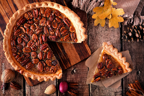 Autumn pecan pie, overhead table scene with cut slice on a rustic wood background photo