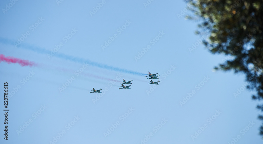 Modern military jet fighter airplanes flying in blue sky. Fighter jets fly together with colorful smoke Modern military jet fighter airplanes flying in blue sky. Fighter jets fly together with colorful smoke