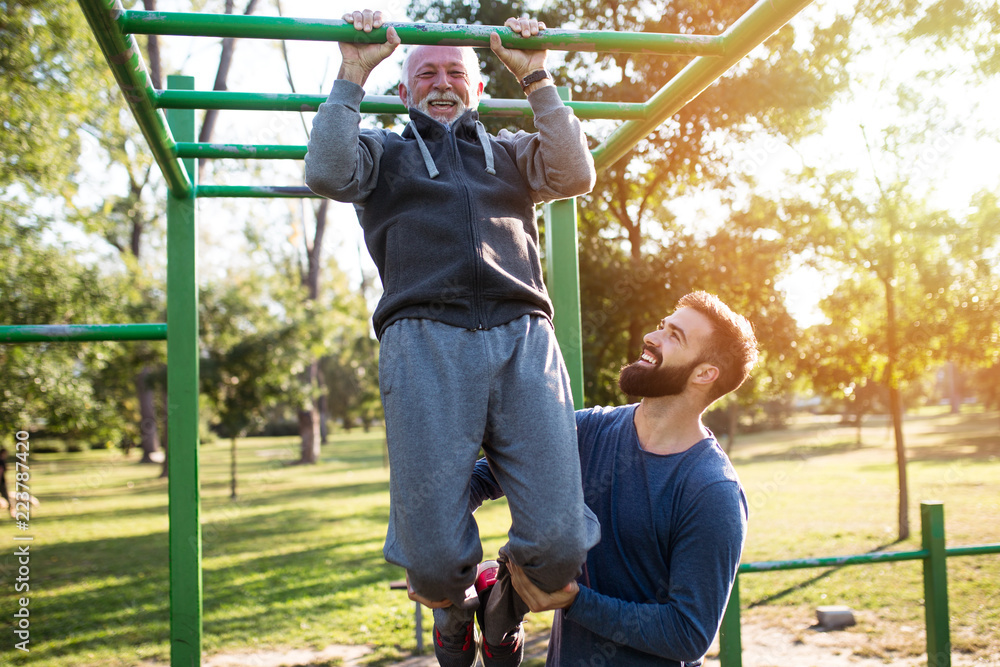 Obraz premium Happy good looking father and son exercising together in park.