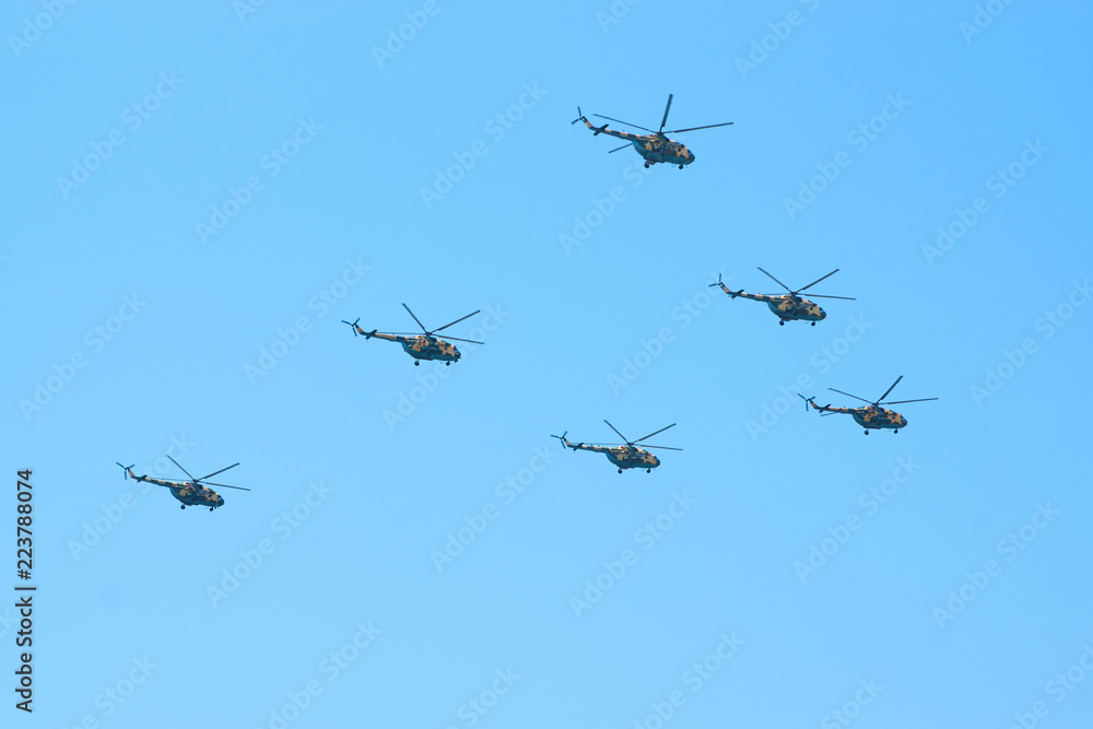 Military helicopters maneuvers in the blue sky. Group combat helicopters in flight during a military demonstration Military helicopters maneuvers in the blue sky. Group combat helicopters in flight during a military demonstration