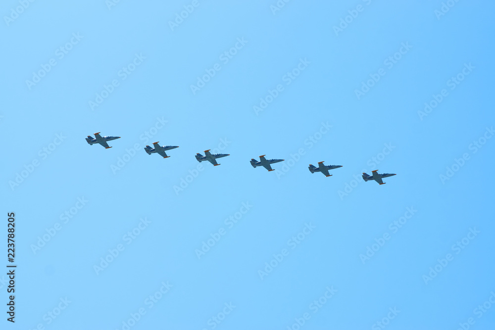 Modern military jet fighter airplanes flying in blue sky. Fighter jets fly together with colorful smoke