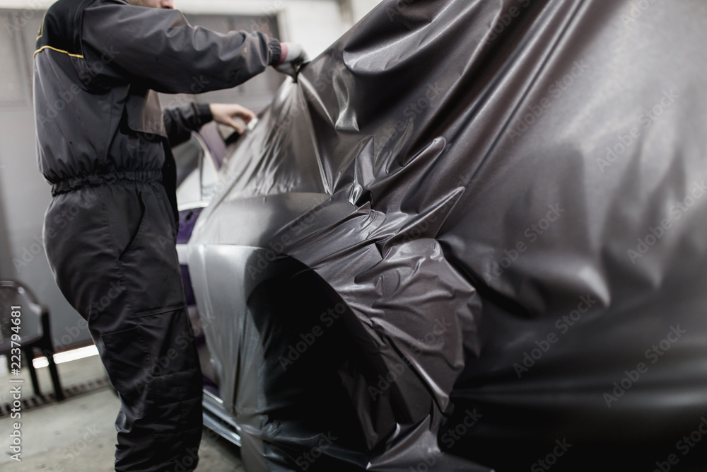 Car wrapping specialist putting vinyl foil or film on car. Selective focus. Car wrapping specialist putting vinyl foil or film on car. Selective focus.