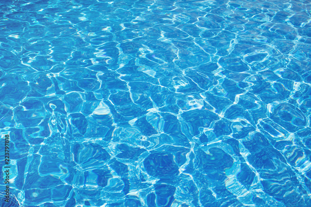 Texture background of blue water with sunlight reflections. Surface of the pool.