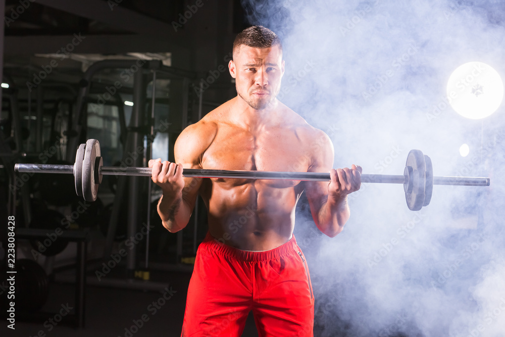 Handsome power athletic man with barbell. Strong bodybuilder with six pack, perfect abs, shoulders, biceps, triceps and chest Handsome power athletic man with barbell. Strong bodybuilder with six pack, perfect abs, shoulders, biceps, triceps and chest