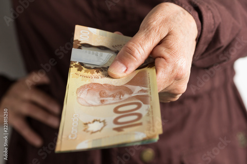 Paper notes from Canada. Dollar. Front view of old woman's hand handling bills. photo