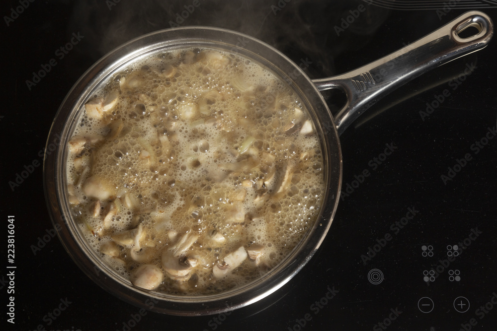 Roasting of champignon mushrooms in butter on a frying pan on the stove Roasting of champignon mushrooms in butter on a frying pan on the stove