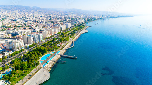 Aerial view of Molos Promenade park on coast of Limassol city centre,Cyprus. Bird's eye view of the jetty, beachfront walk path, palm trees, Mediterranean sea, piers, urban skyline and port from above © f8grapher