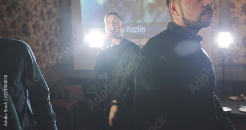 A young man is singing in a karaoke club.