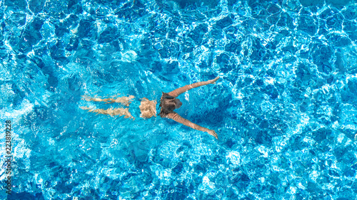 Aerial drone view of active girl in swimming pool from above, yong woman swims in blue water, tropical vacation, holiday on resort concept 
