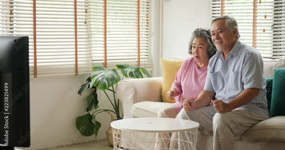 Asian senior couple watching television movie with excite emotion together in living room. People with relaxation, old age, retirement, senior lifestyle family concept. Asian senior couple watching television movie with excite emotion together in living room. People with relaxation, old age, retirement, senior lifestyle family concept.
