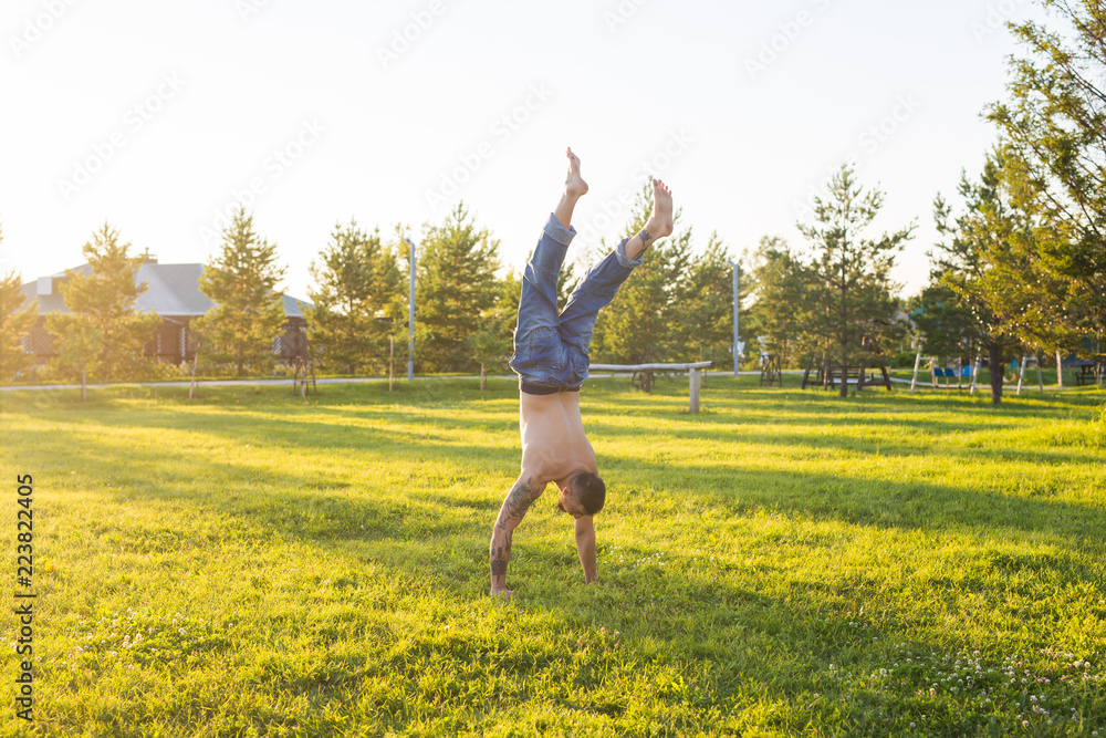 Yoga, fitness and healthy lifestyle concept - man doing a handstand on summer nature Yoga, fitness and healthy lifestyle concept - man doing a handstand on summer nature