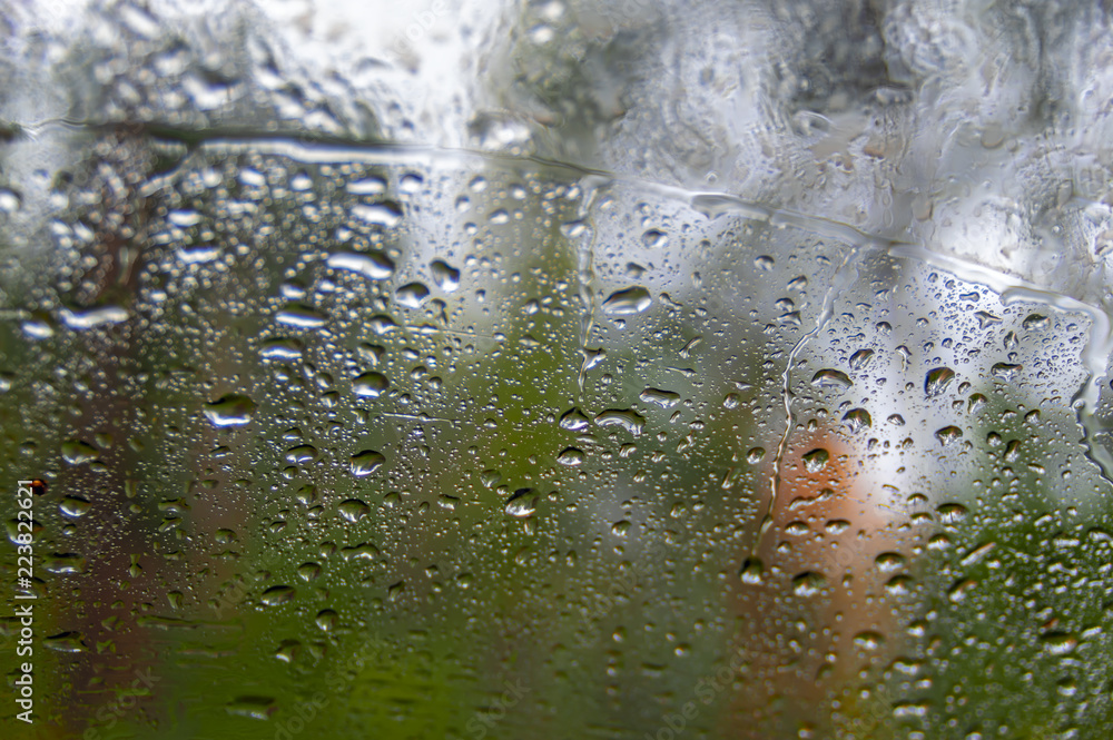 Drops of rain on a window. Blur autumn forest in background. Autumnal rainy landscape.