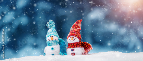 little knitted snowmans on soft snow on blue background