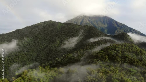 Aerial view of Sumaco Volcano with rainbow, tilt down to Laguna Wawa Sumaco, a volcanic crater lake surrounded with misty montane rainforest. In the Ecuadorian Amazon.