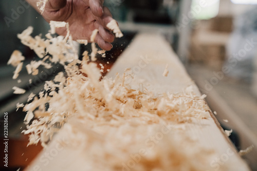 Papier peint hand sweeps sawdust from a wooden beam