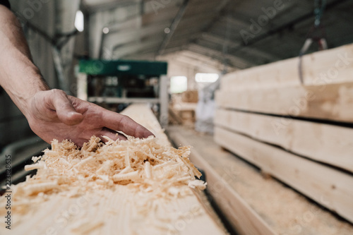 hand sweeps sawdust from a wooden beam