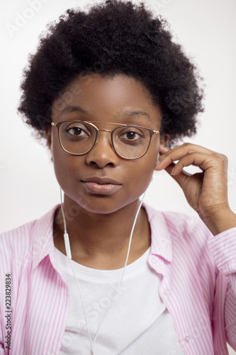 Foto good looking student in stylish shirt taking off earphones