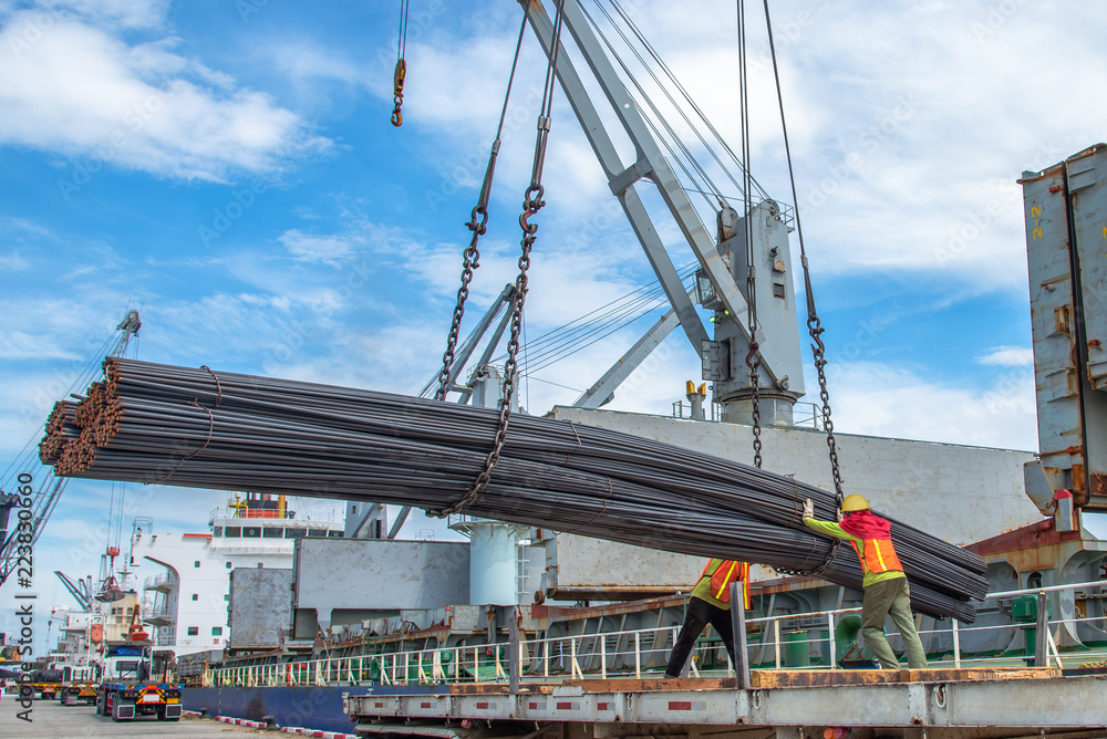 Fototapeta premium bundle of steel rod being loading discharging in port terminal, handle by gang of stevedore labor , shipment cargo in transition from land and sea transport services.