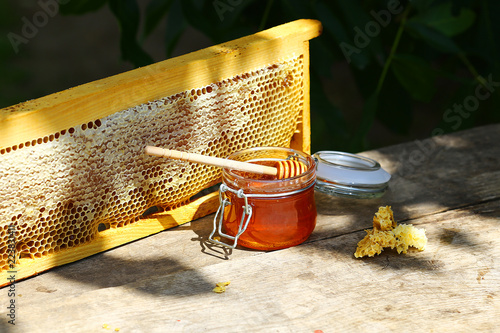 Photography jar of fresh honey in a glass jar on an old table on a apiary
