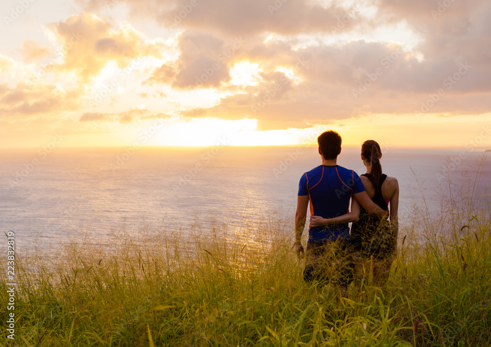 Young couple standing together watching the sunset. 