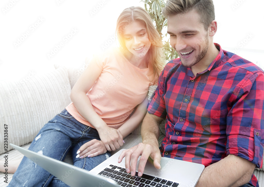 Happy modern couple surfing the net and working on laptop at home Happy modern couple surfing the net and working on laptop at home