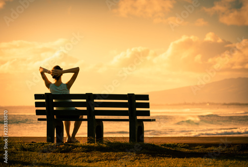 Young woman sitting back relaxing watching the beautiful sunset. 