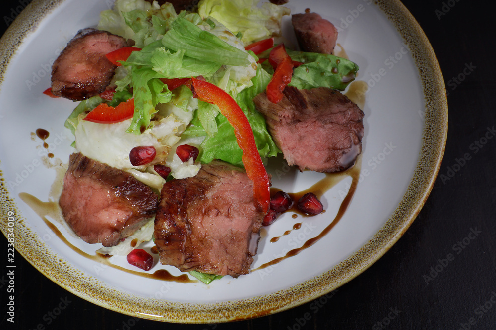 Meat hot salad with beef tenderloin, iceberg salad and garnet decorated with pomegranate Meat hot salad with beef tenderloin, iceberg salad and garnet decorated with pomegranate