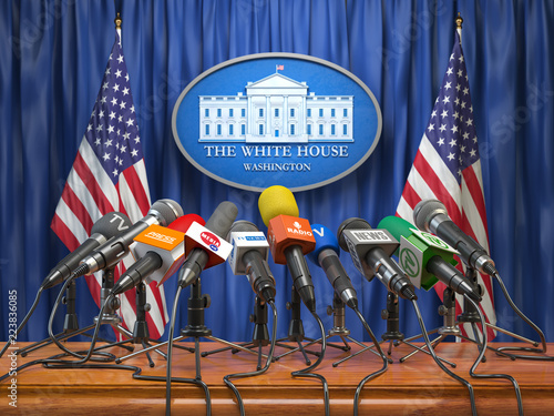 Press conference of president in the White House Washington.  Microphones  of all media with USA flags and White House sign.