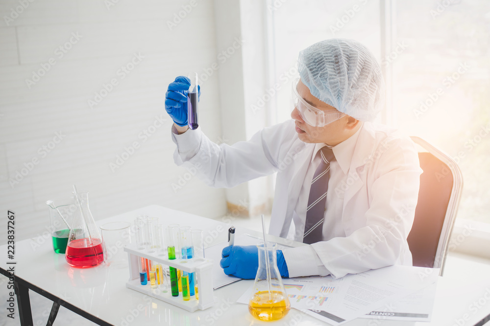 Fototapeta premium Scientists or researchers look at multicolor test tubes in science labs. Science, chemistry, biology concept.